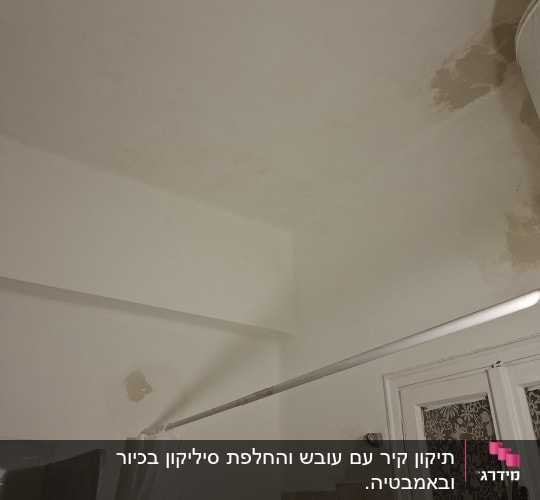 קיר ותקרה עם סימני רטיבות ותיקונים
